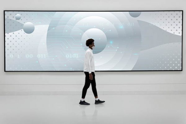 Man walking in front of a large billboard